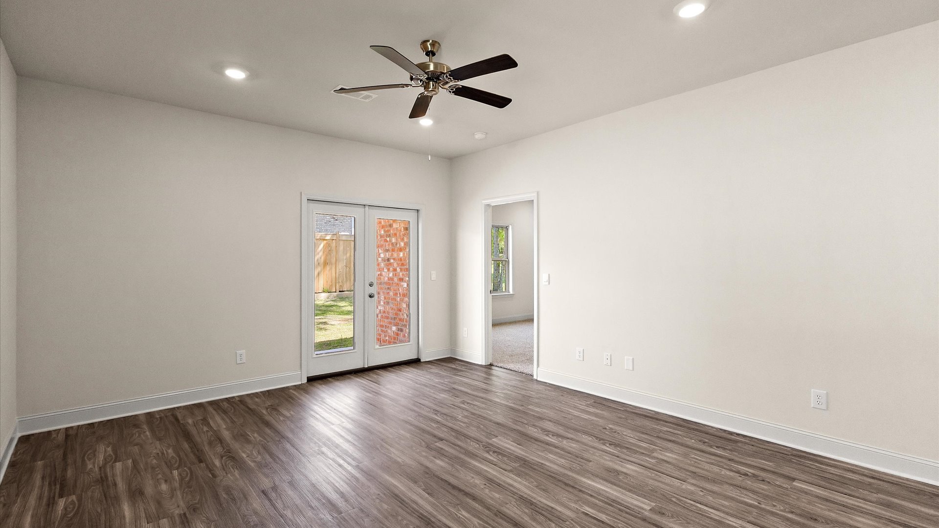 Living area adjacent to a bedroom with a back door.
