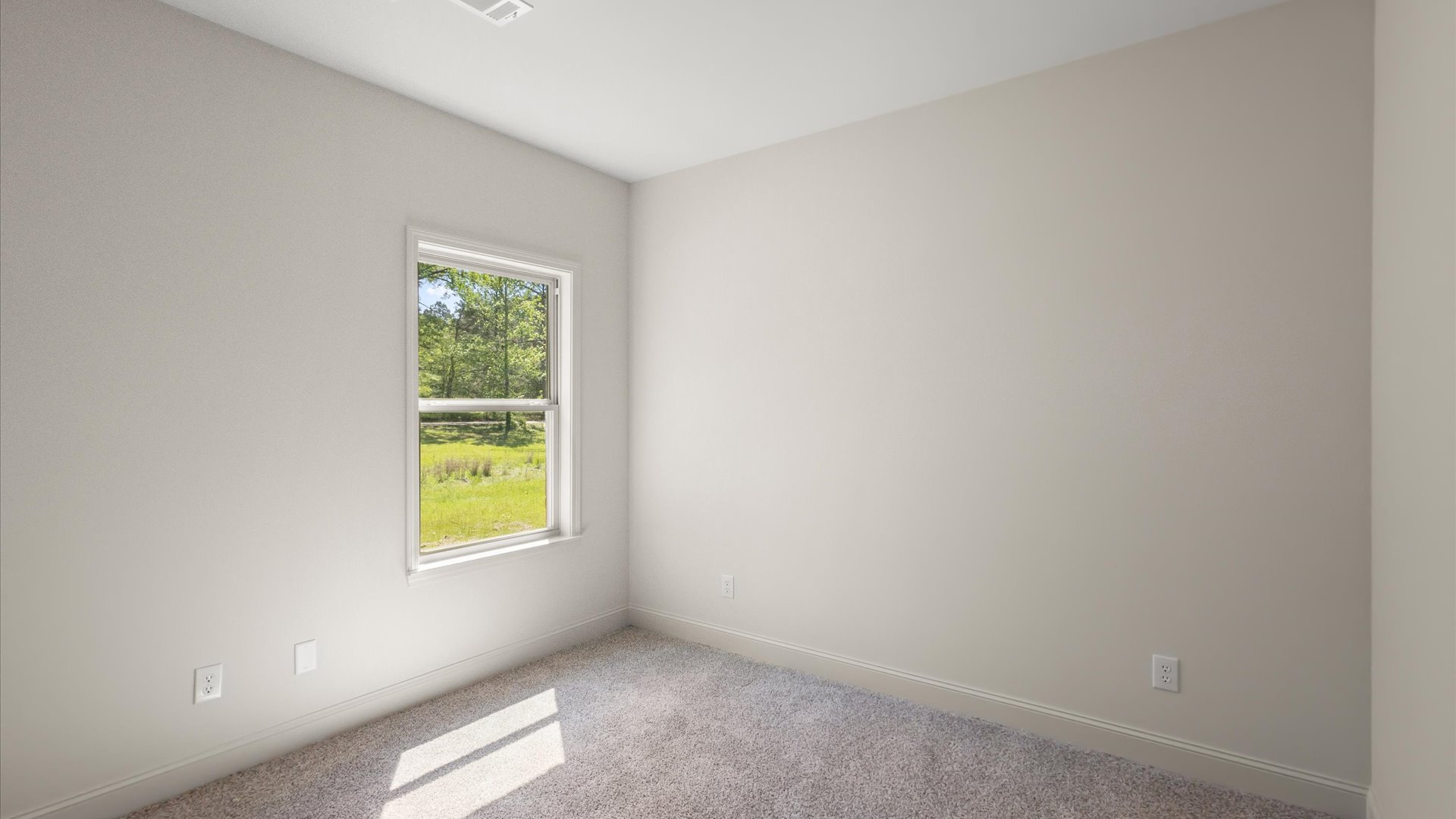 A second bedroom with a window and carpeted floors.