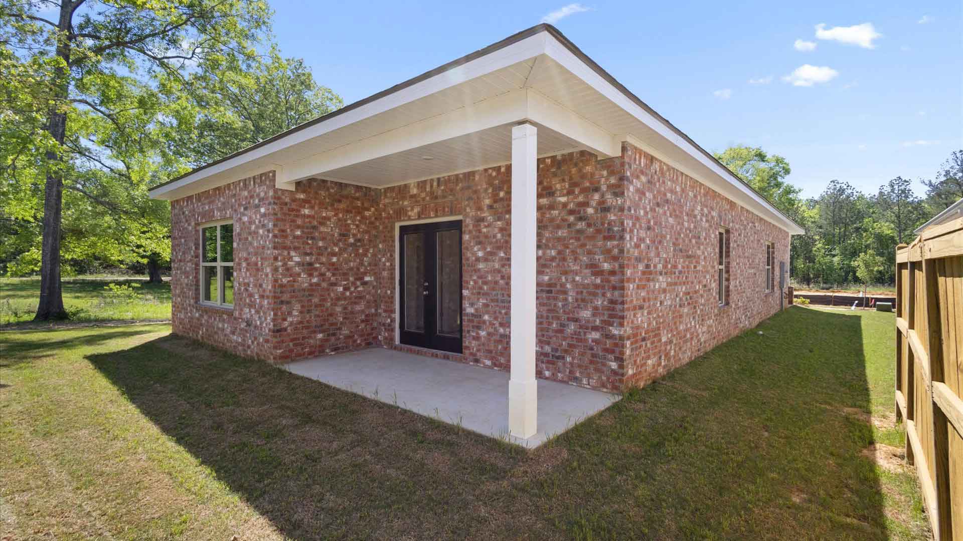 one-story exterior rear view of home with brown brick, a double back door and a patio.