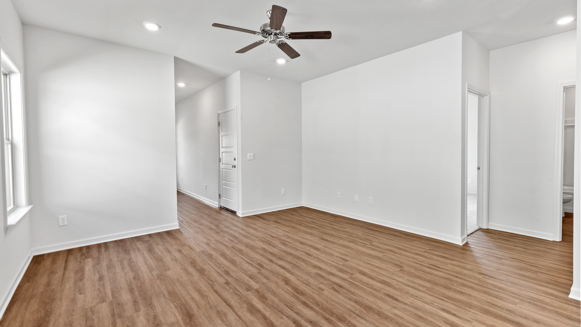 spacious living area featuring brown floors, and white walls