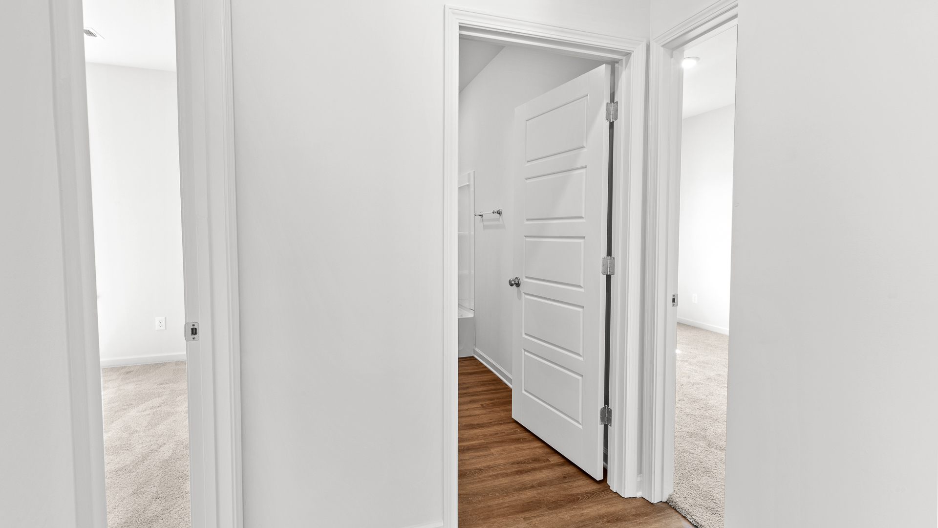hallway view featuring previews of bedrooms on either side and a bathroom in the middle