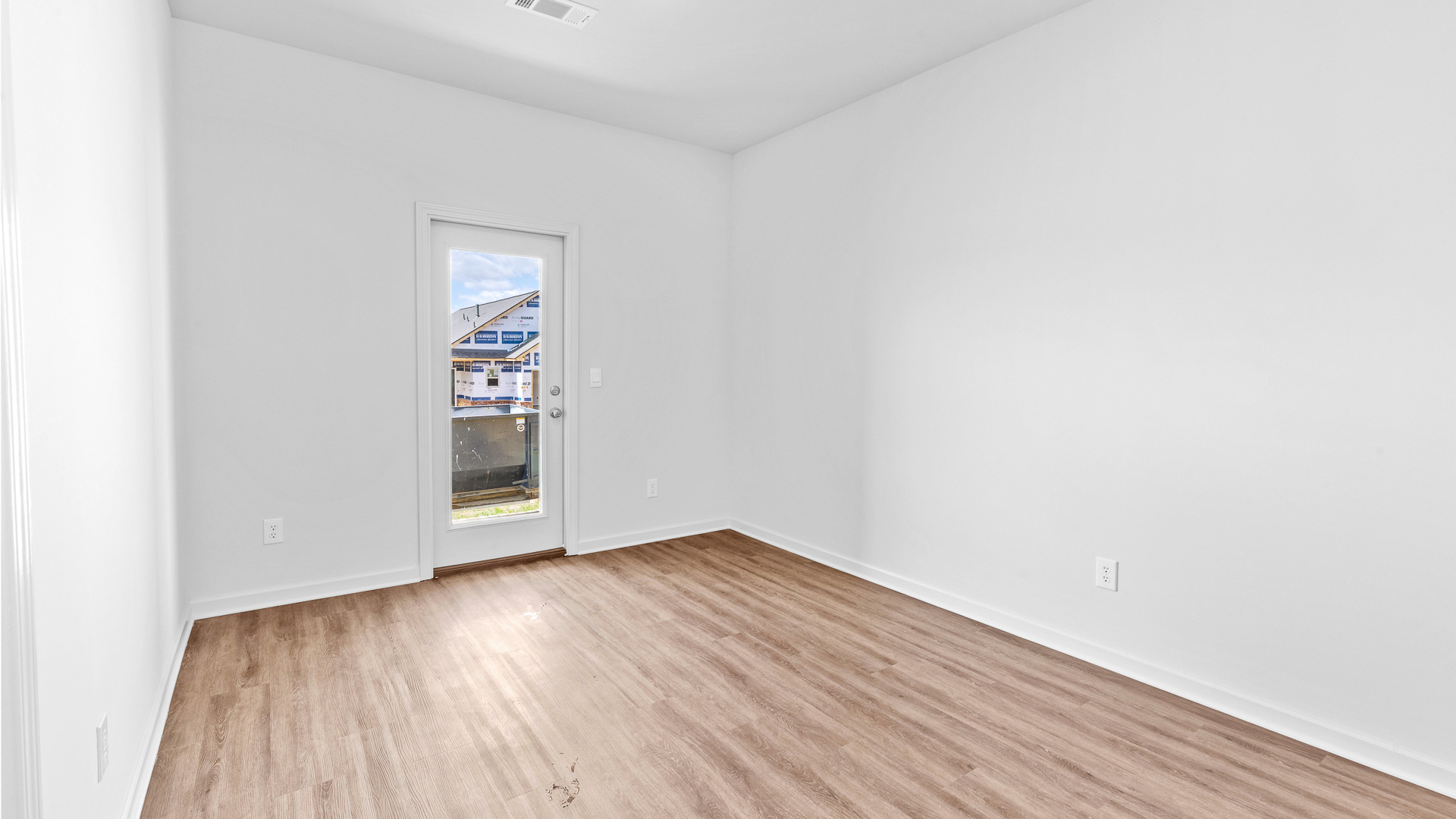 room featuring brown flooring and a window leading to the backyard