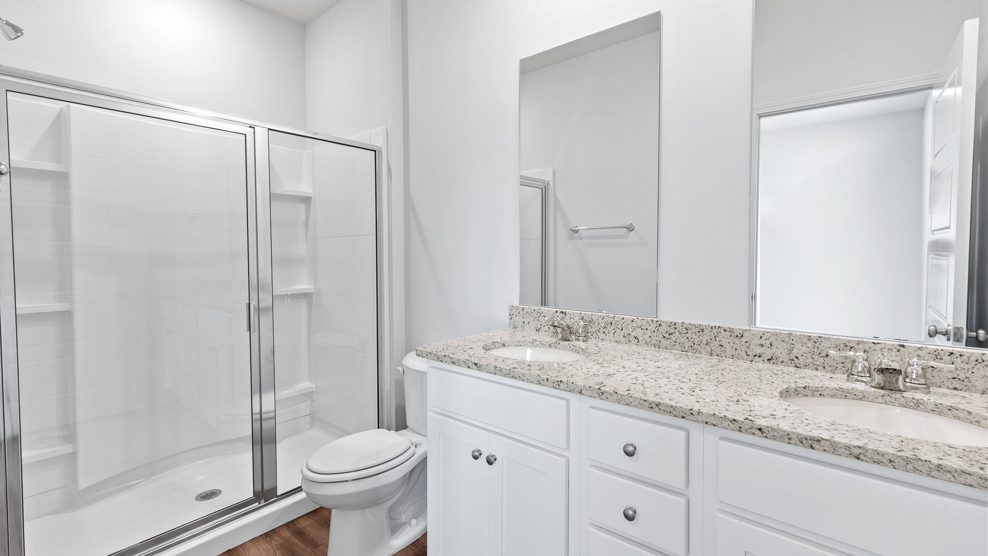 spacious bathroom featuring dual vanity sinks, a toilet and a walk in shower
