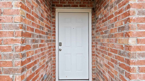 Front porch with red/brown brick and white door.