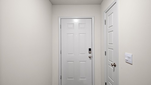 Front entryway and foyer with hardwood floors and door to the garage on the right.
