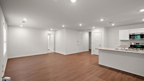 Different view of the open concept space of the kitchen, dining, and living area with glass door back porch and large double window.