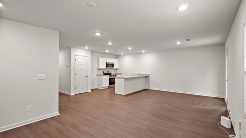 Spacious open concept space of the kitchen, dining, and living area with glass door back porch and large double window.