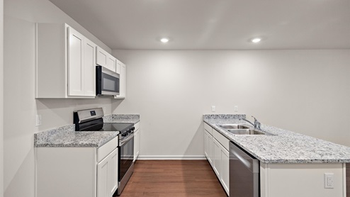 Kitchen with granite countertops, large island, white cabinets, and stainless steel appliances.