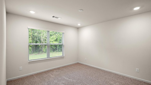Bedroom with large double window and carpeted floors.
