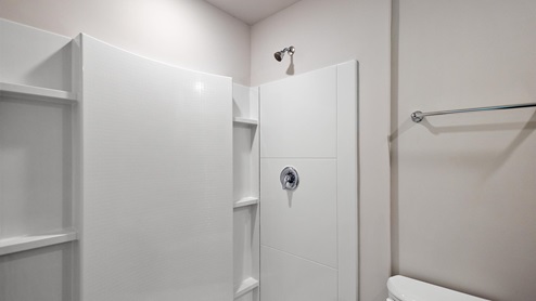 Walk in shower with white tile and shelving.