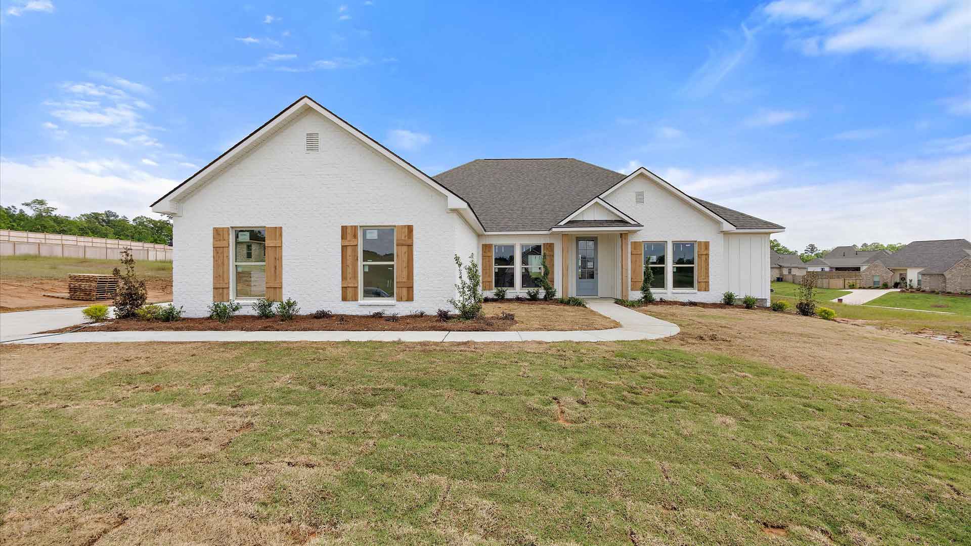 This single story home has exterior brick and driveway under a blue sky.
