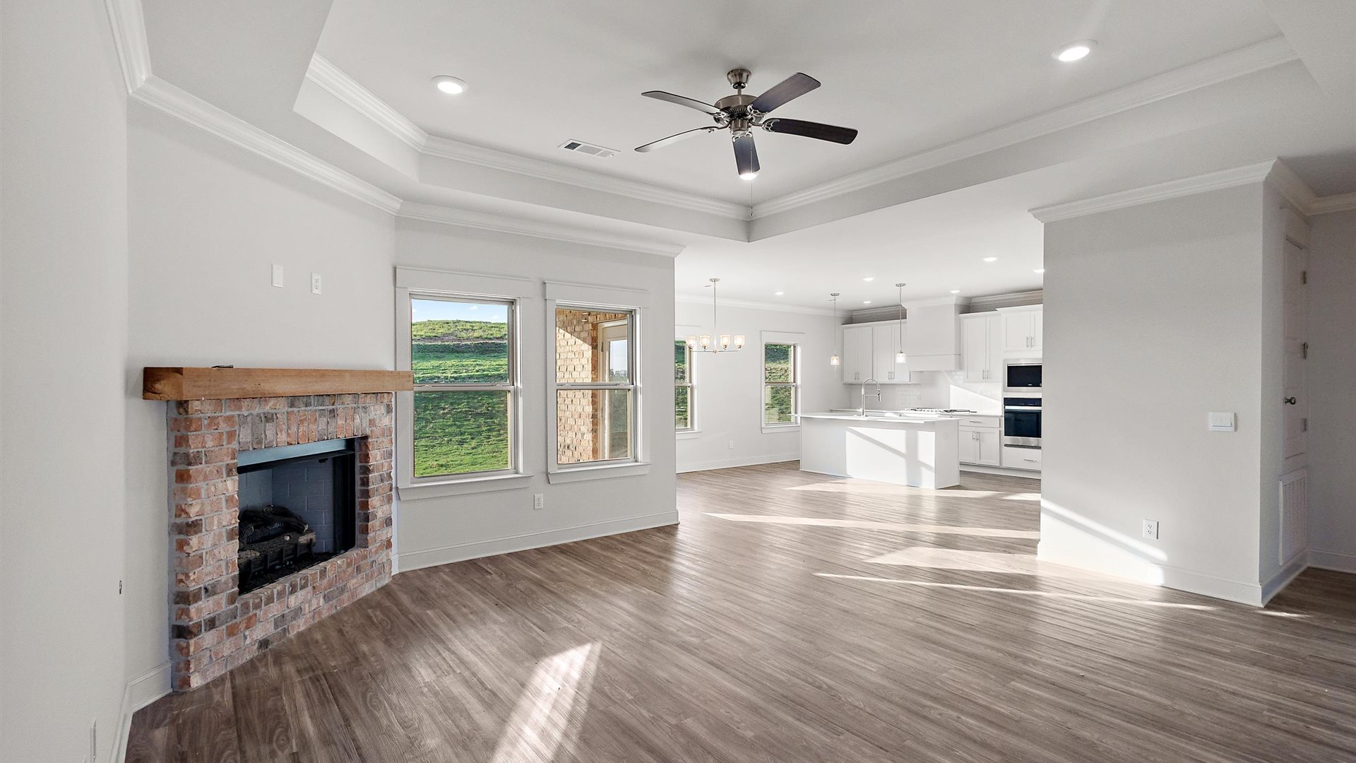 Living room looking to dining, kitchen areas features electric fire place, natural light, with fresh open concept flow