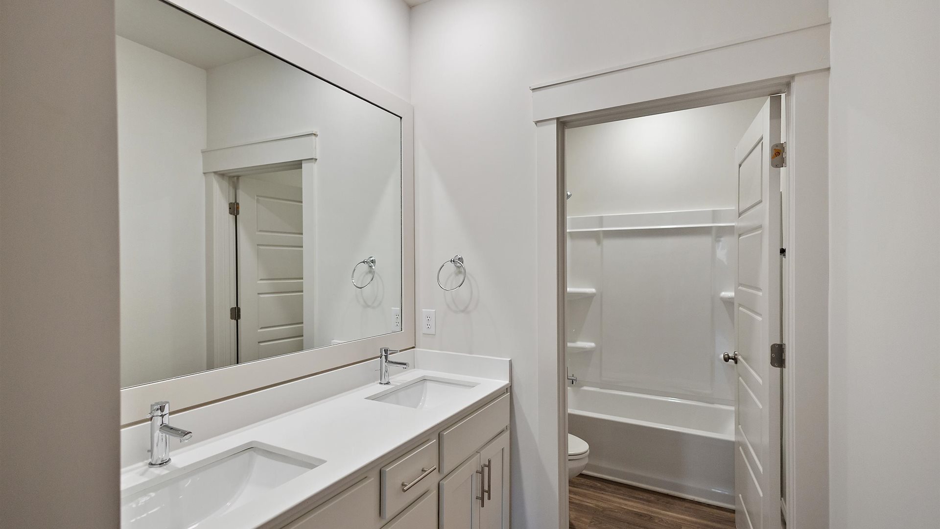 Family full bathroom with stylish vanity, mirror, polished fixtures, cabinets, tub-shower combo in Cornerstone