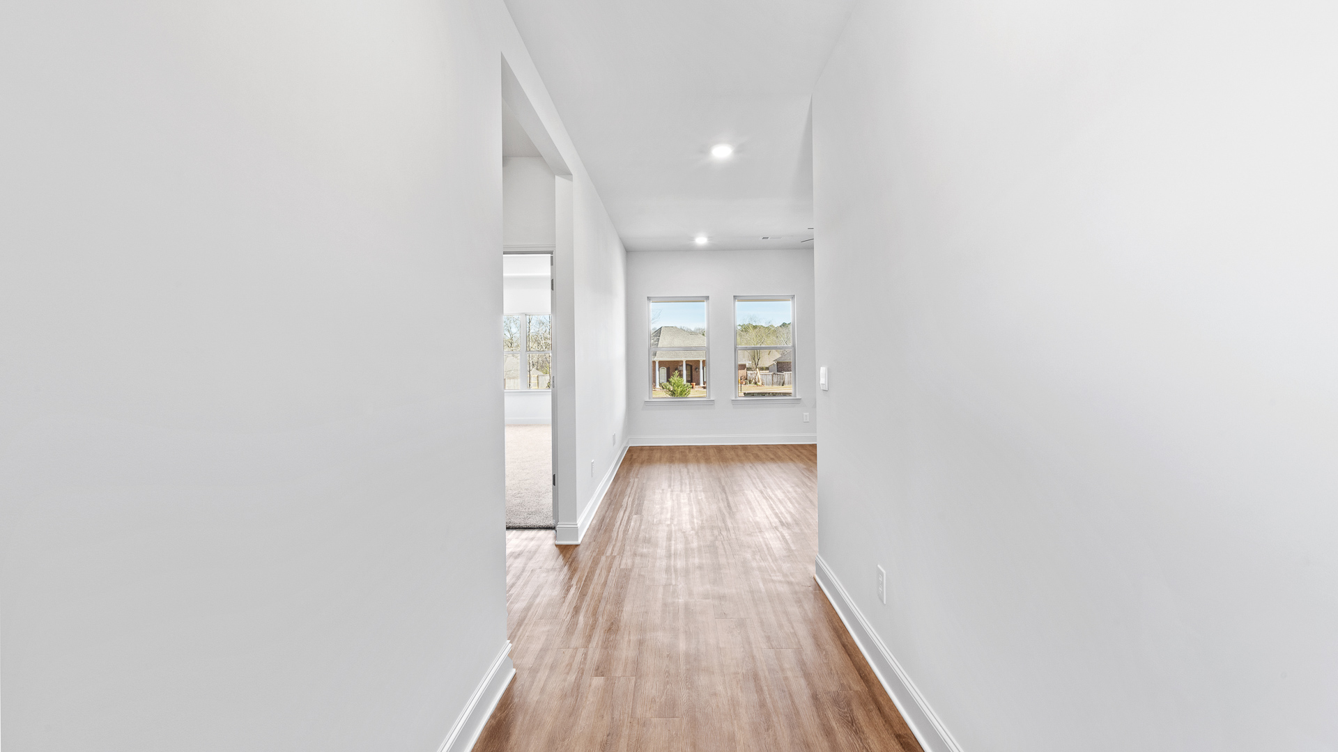 Front entryway of home with light walls and brown wood like tile flooring.