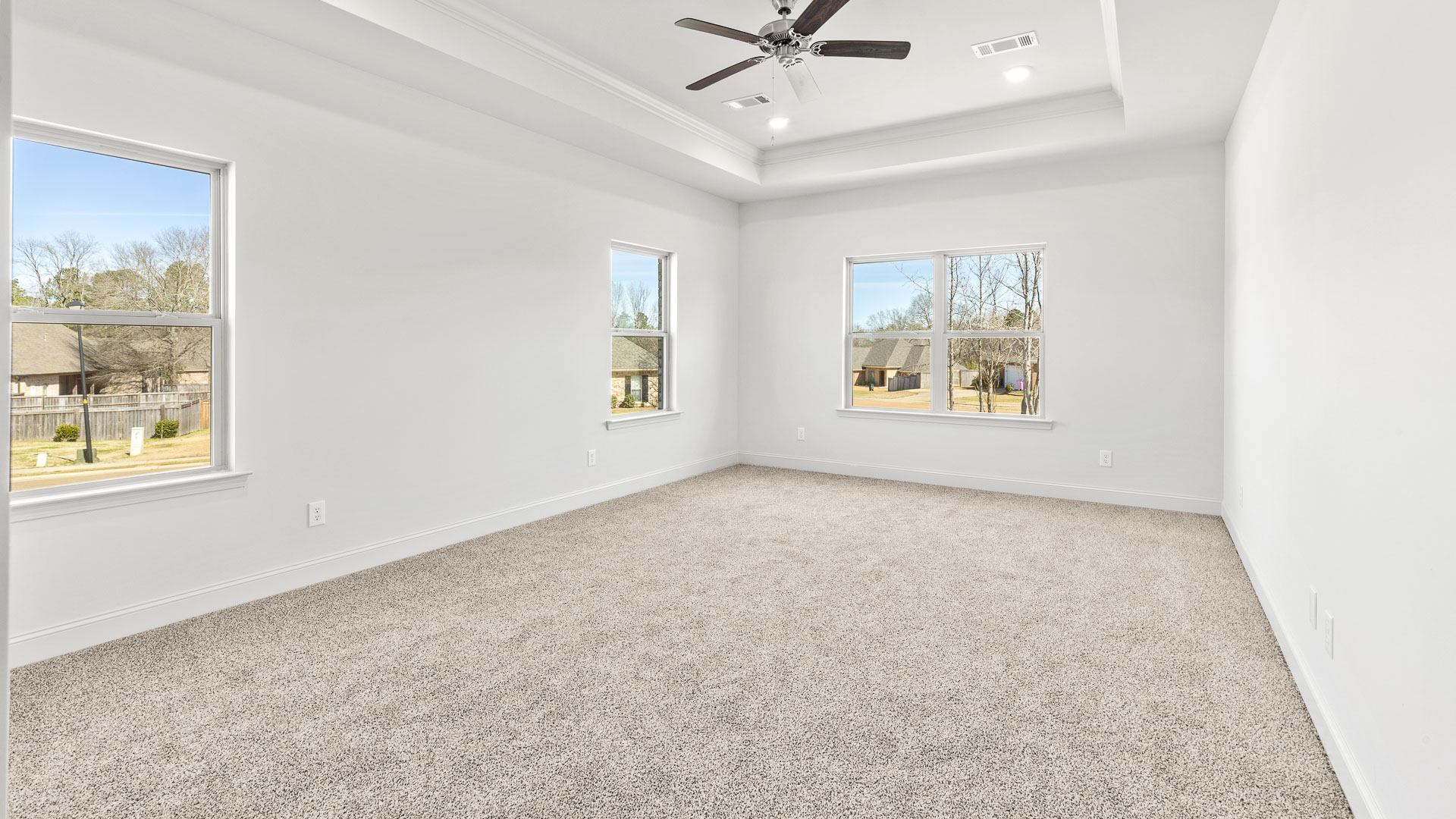 Bedroom with carpeted floors and several windows for natural lighting.