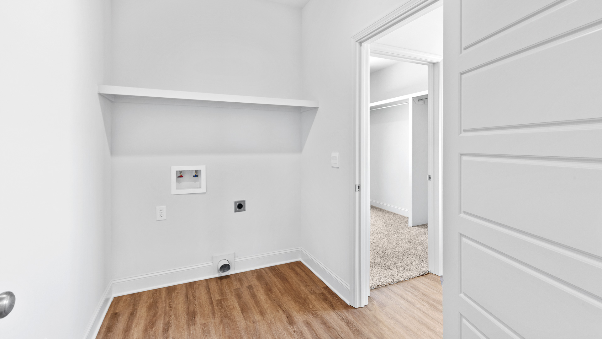 Laundry space with wood like tile flooring and built in storage space.