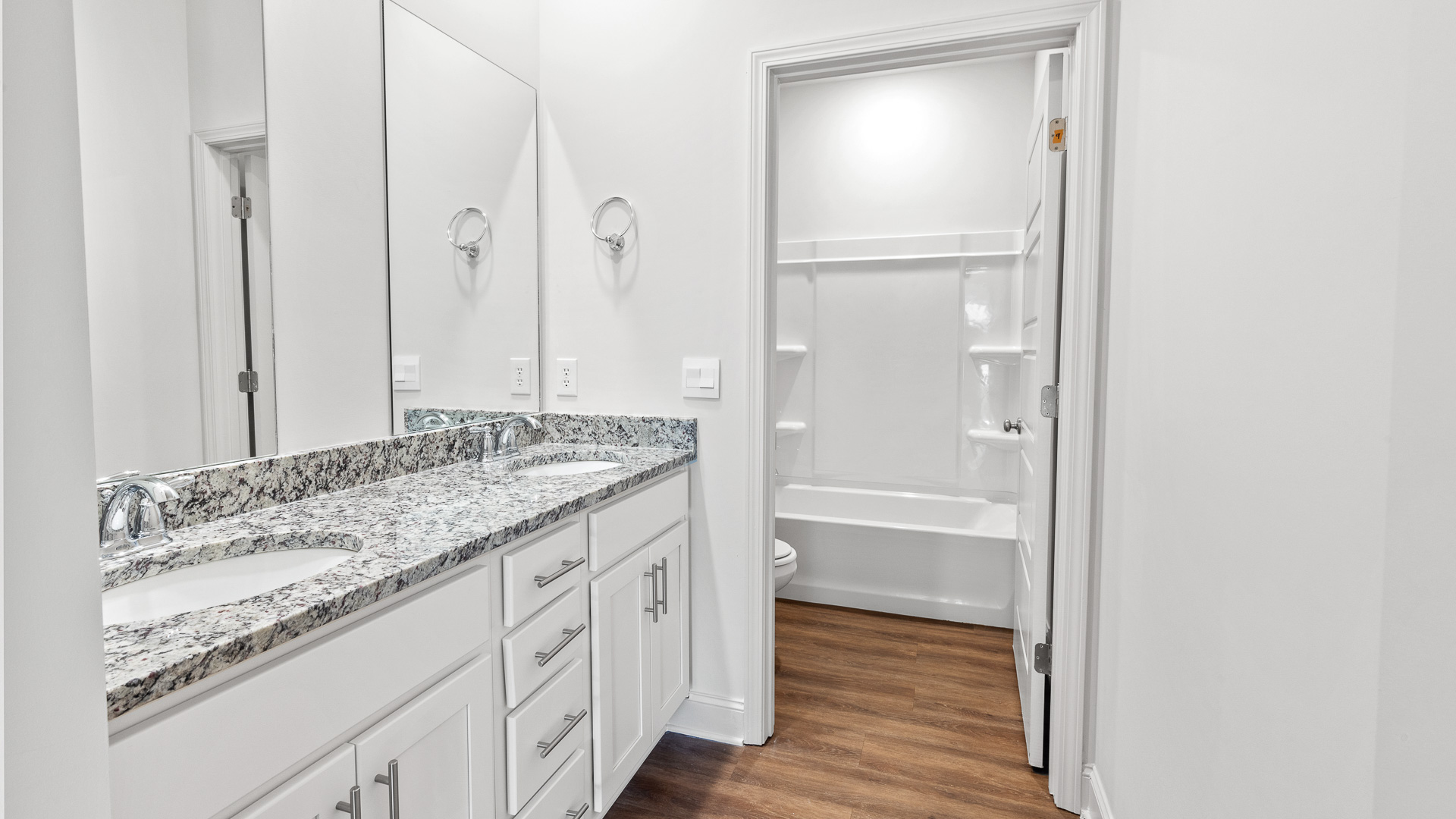 Bathroom with double vanity sinks and separate door for toilet and shower.