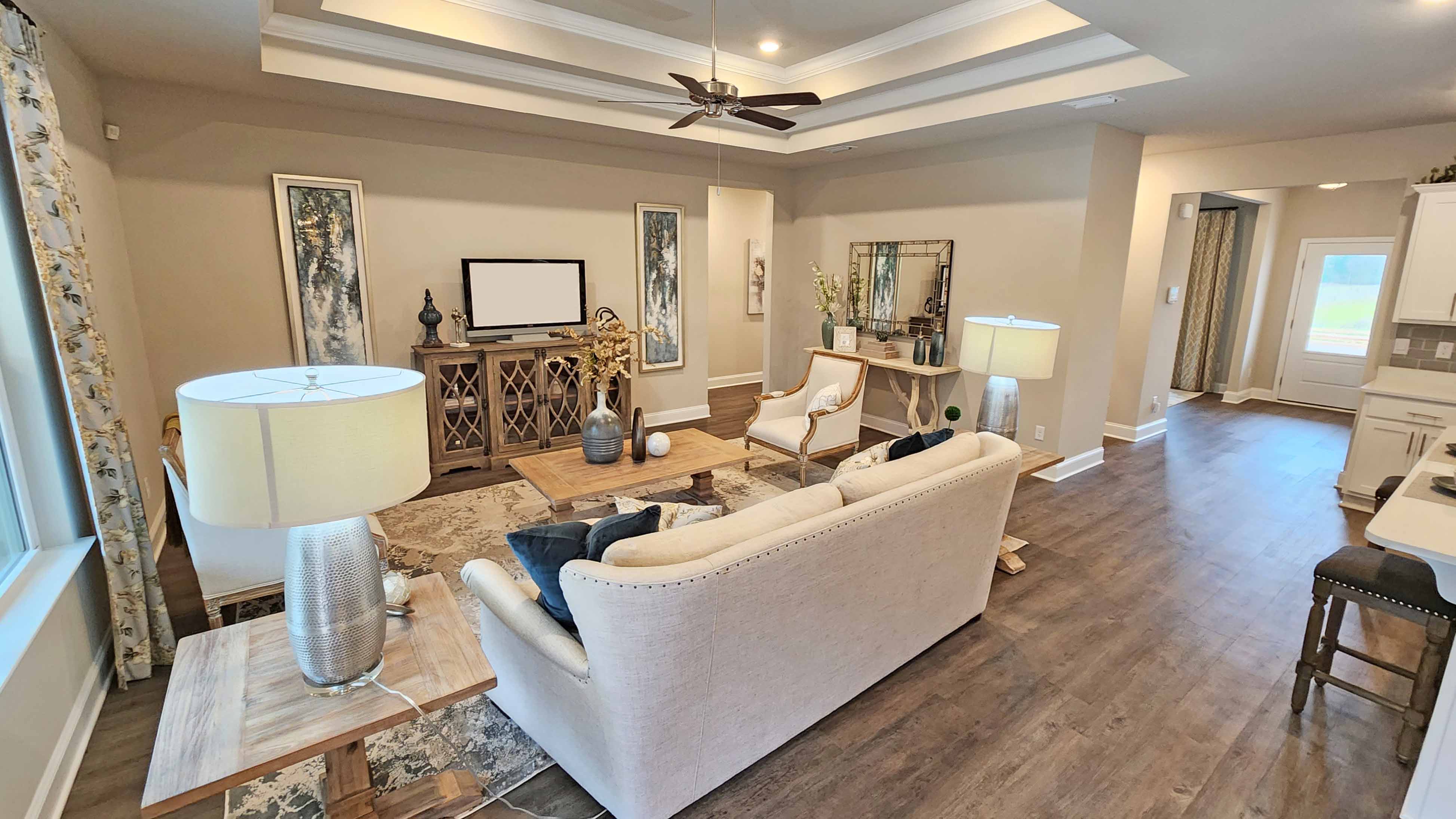 living space with tray ceilings, hardwood floors, and ceiling fan