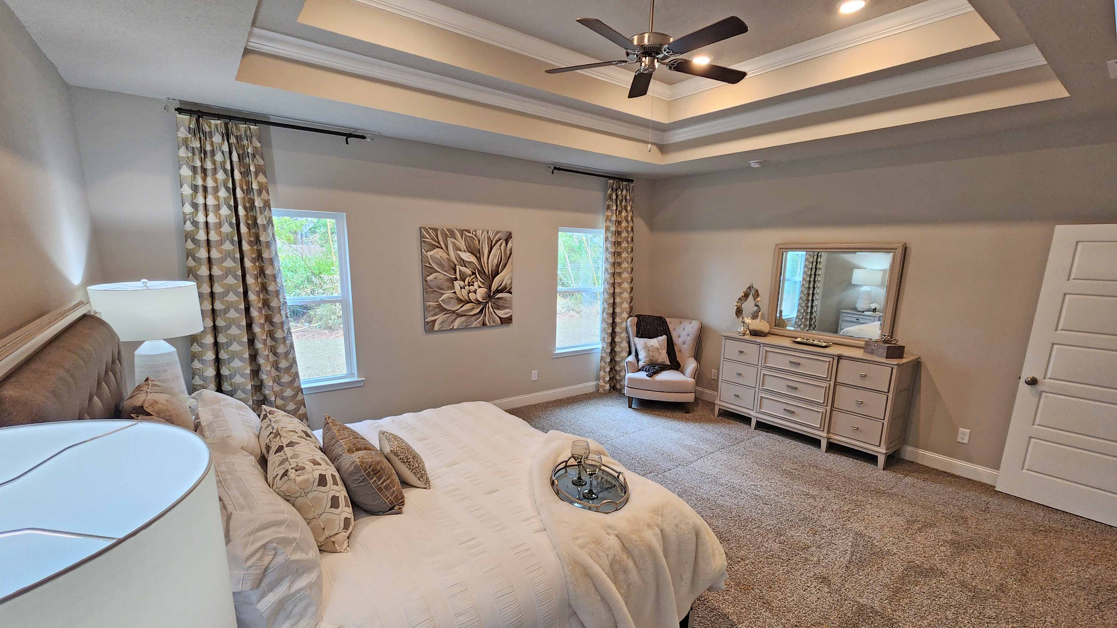 primary bedroom with carpeted floors, tray ceilings, and ceiling fan