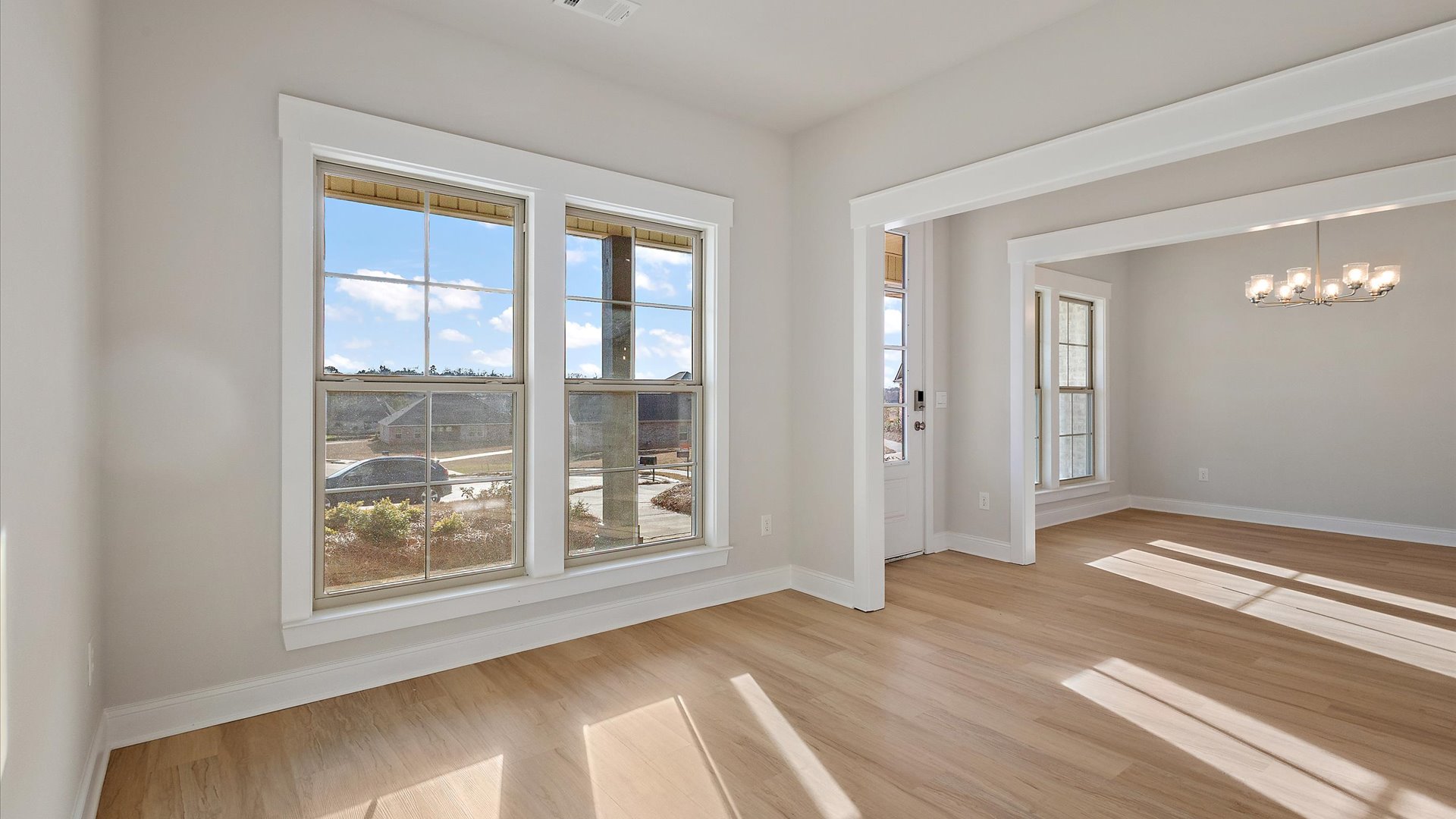 Living room looking toward dining, kitchen and outdoor areas with natural light and smooth open-concept flow
