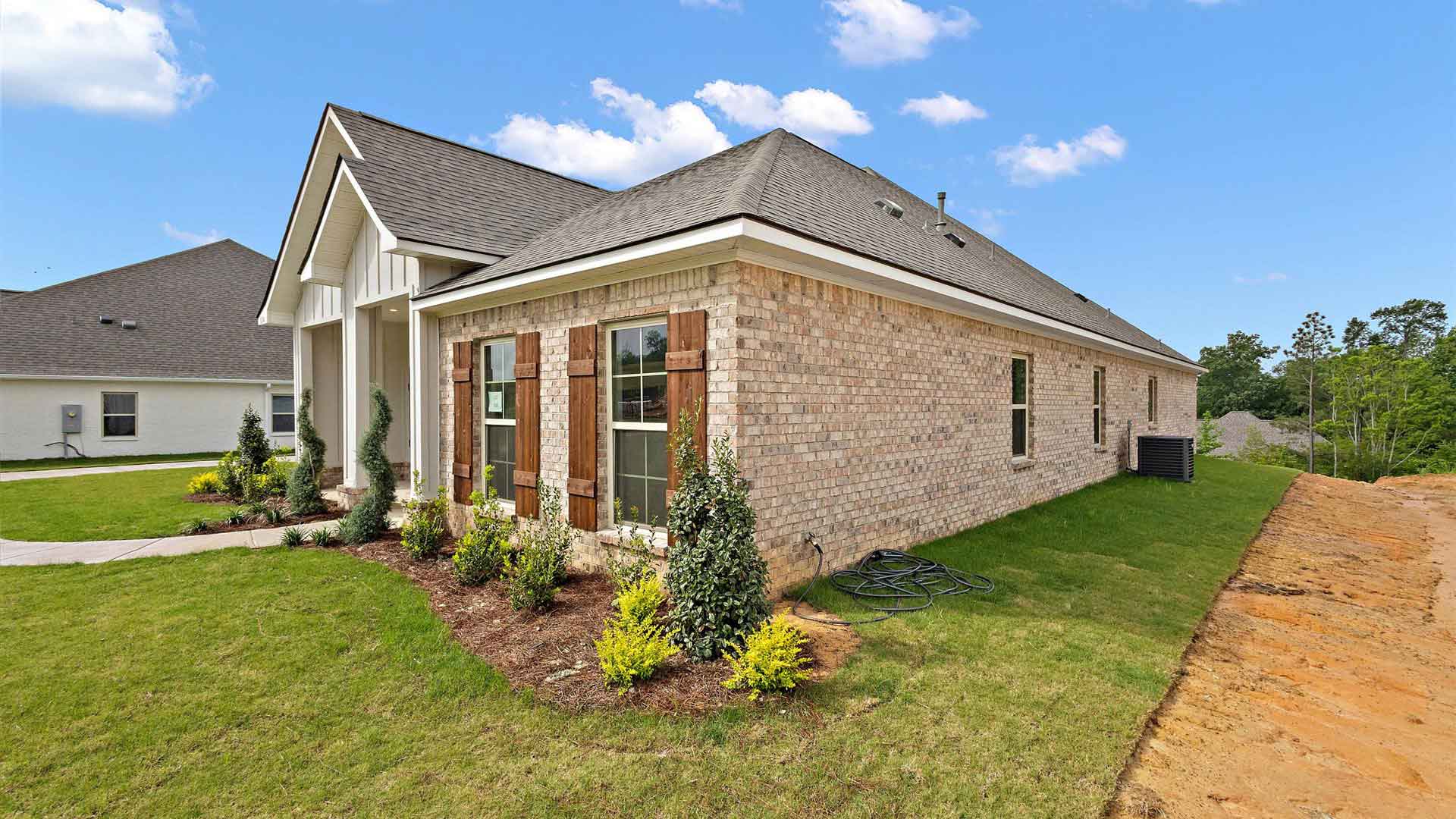 Front exterior of the McKenzie floorplan featuring white siding, light brown brick accents and brown shutters