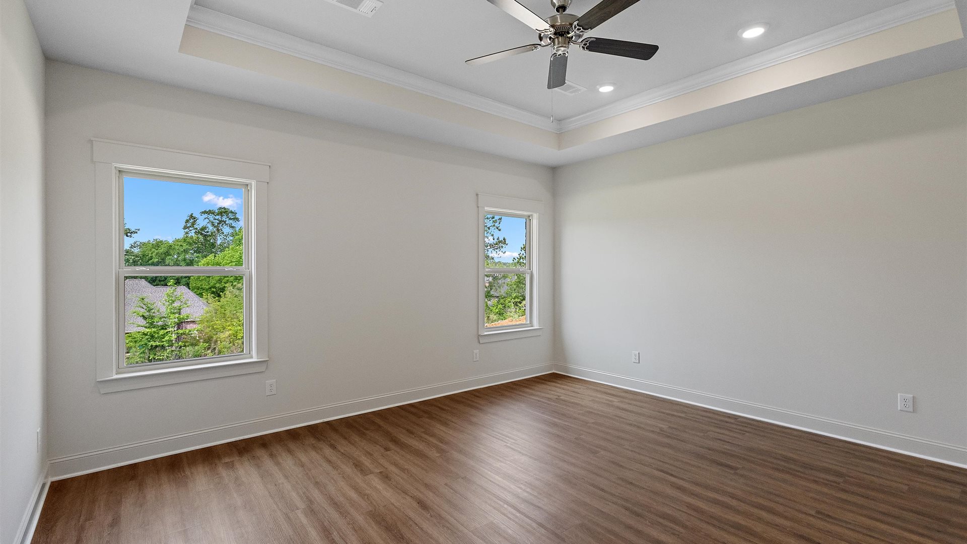 bedroom with brown flooring, and white walls, and 2 windows on the back wall