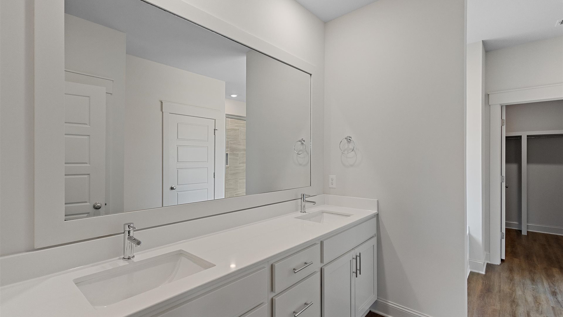 dual vanity sink bathroom featuring white cabinetry and a large mirror above