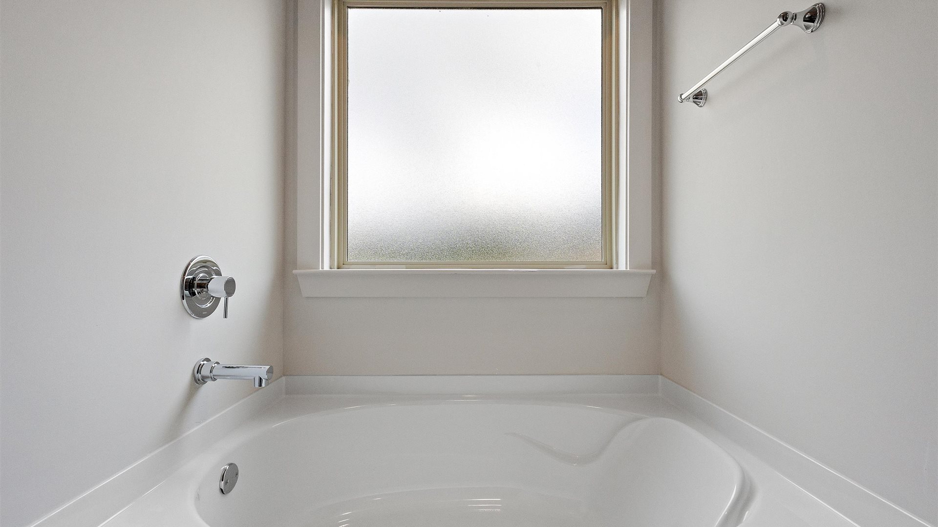 stand alone bath tub in the primary bathroom with a screened window above