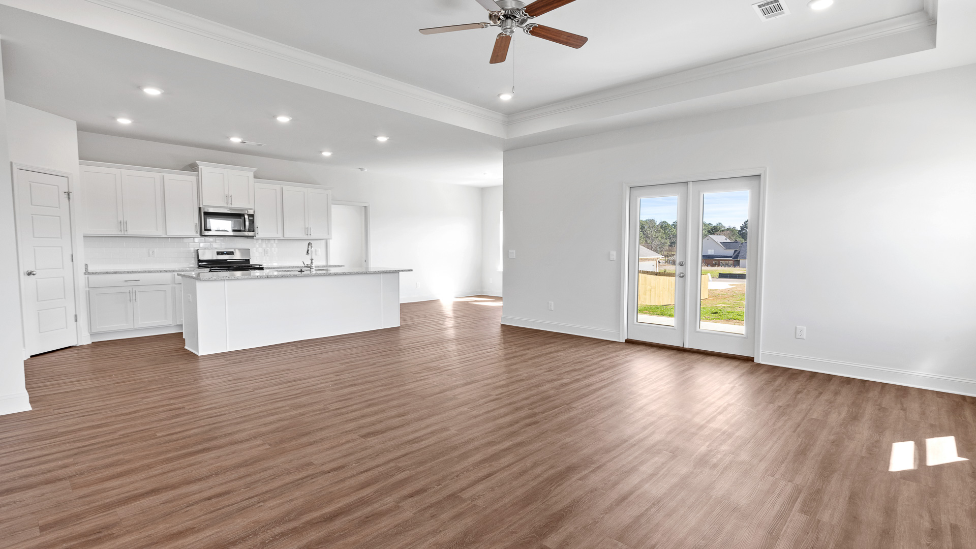 open living space with tray ceilings, hardwood floors, ceiling fan, and recessed lighting