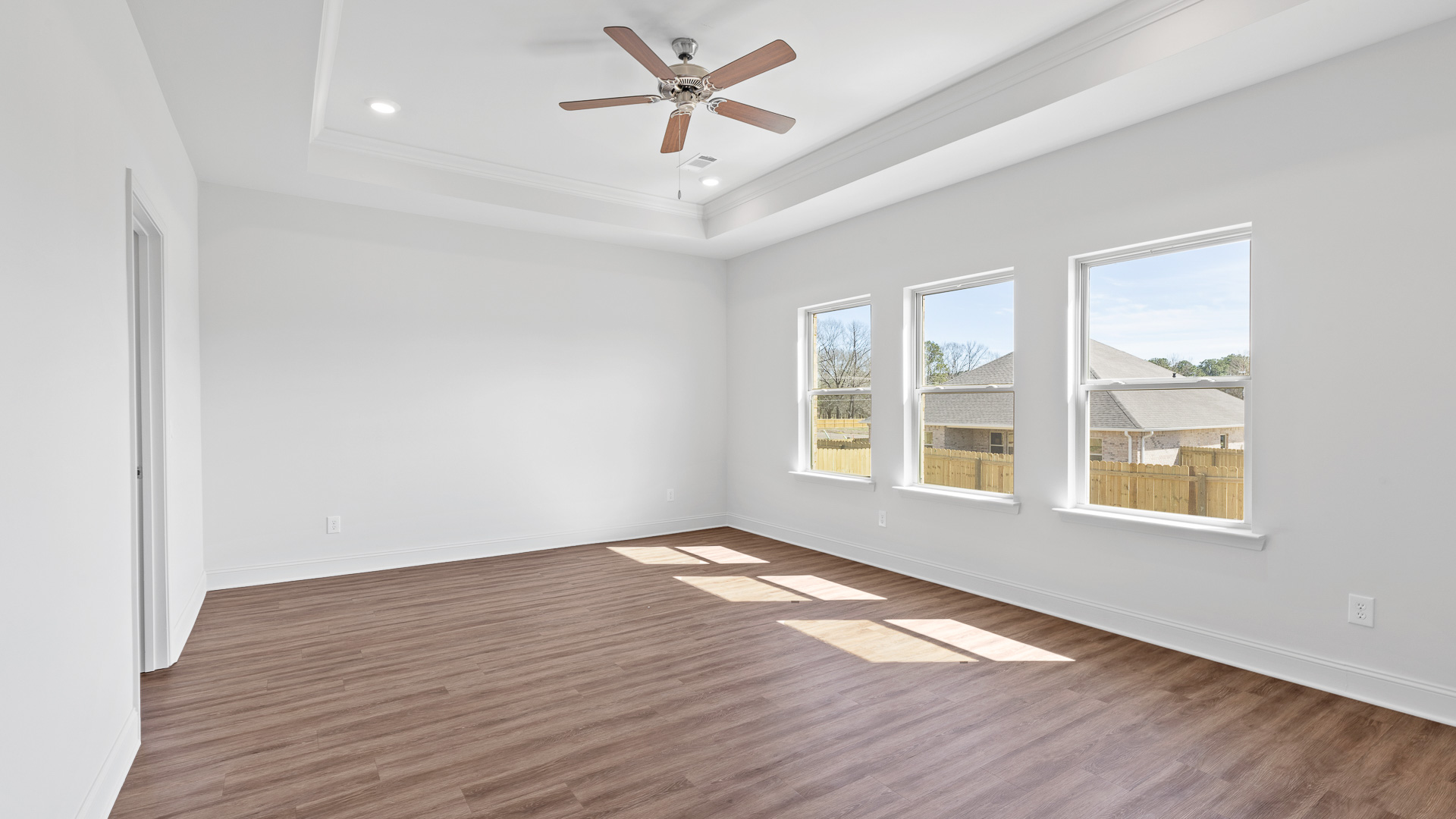 primary bedroom with ceiling fan, hardwood floors, tray ceilings, and recessed lighting