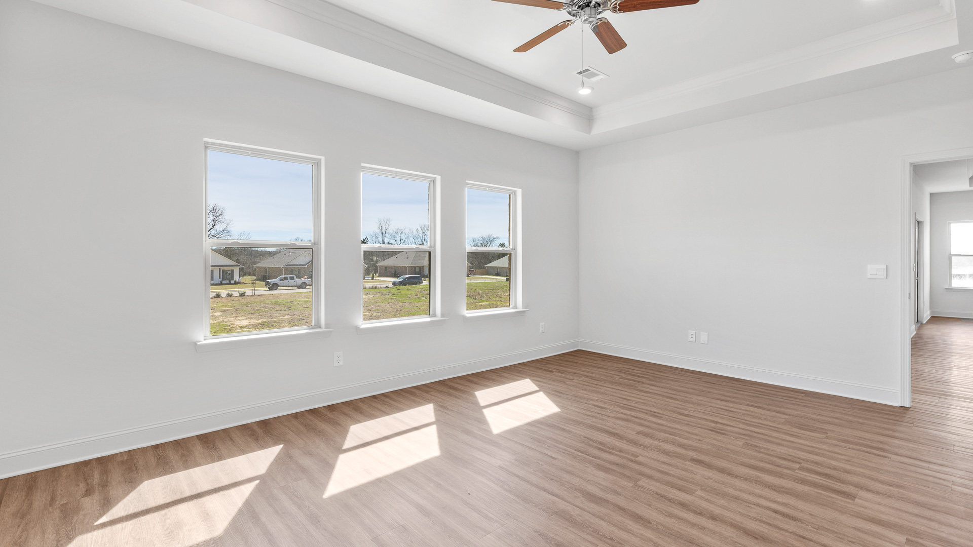 primary bedroom with ceiling fan, hardwood floors, tray ceilings, and recessed lighting