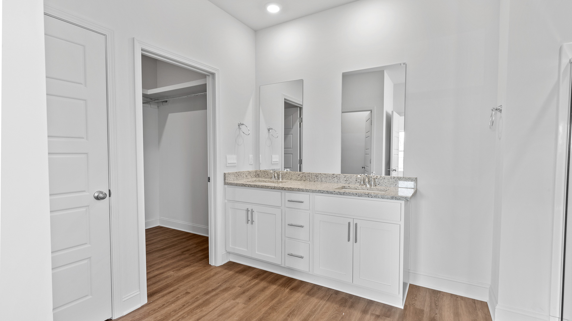 double vanity with granite countertops, recessed lighting, hardwood floors, leading to walk-in closet