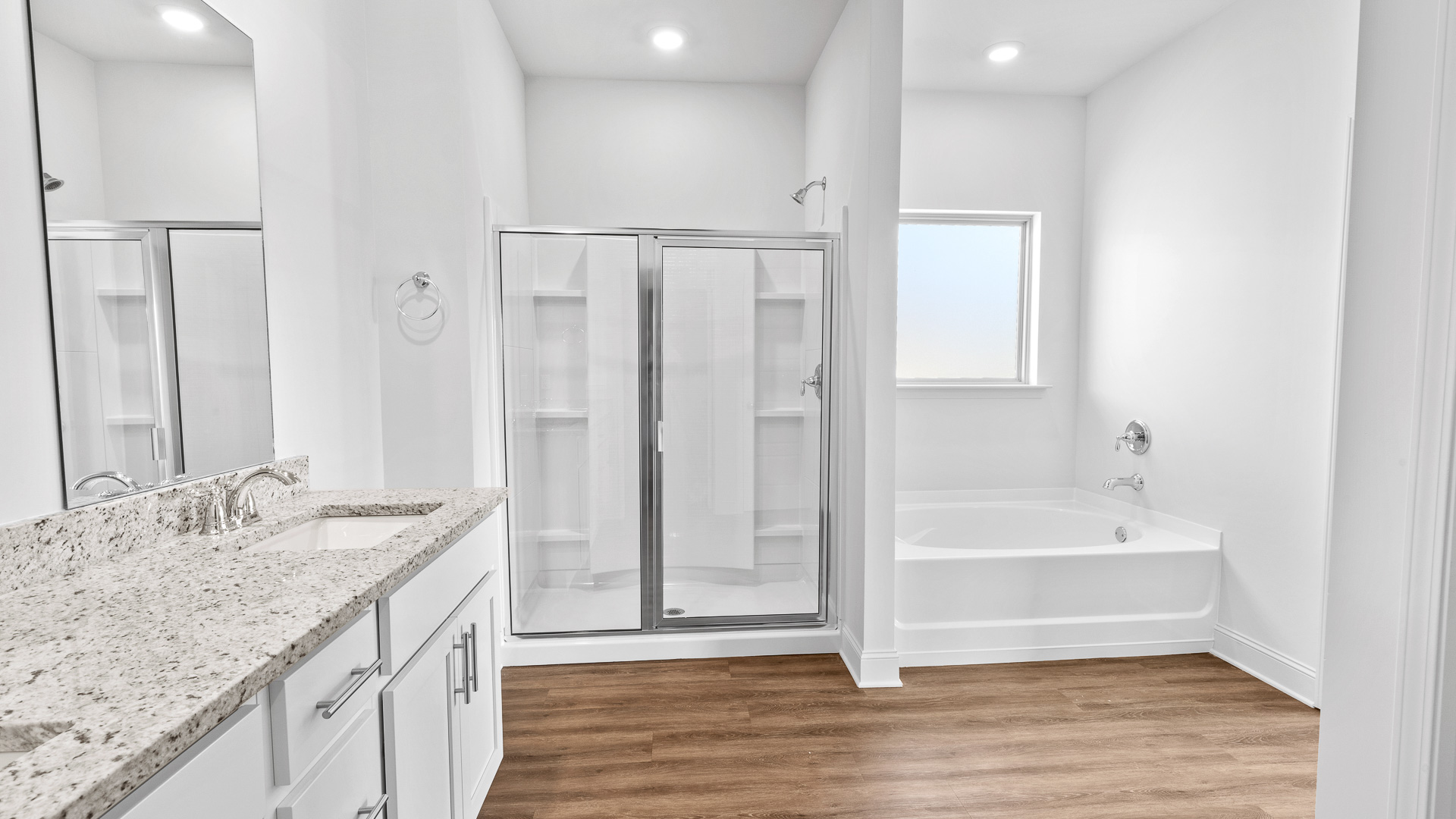 double vanity with granite countertops, stand up shower, and garden tub with frosted window