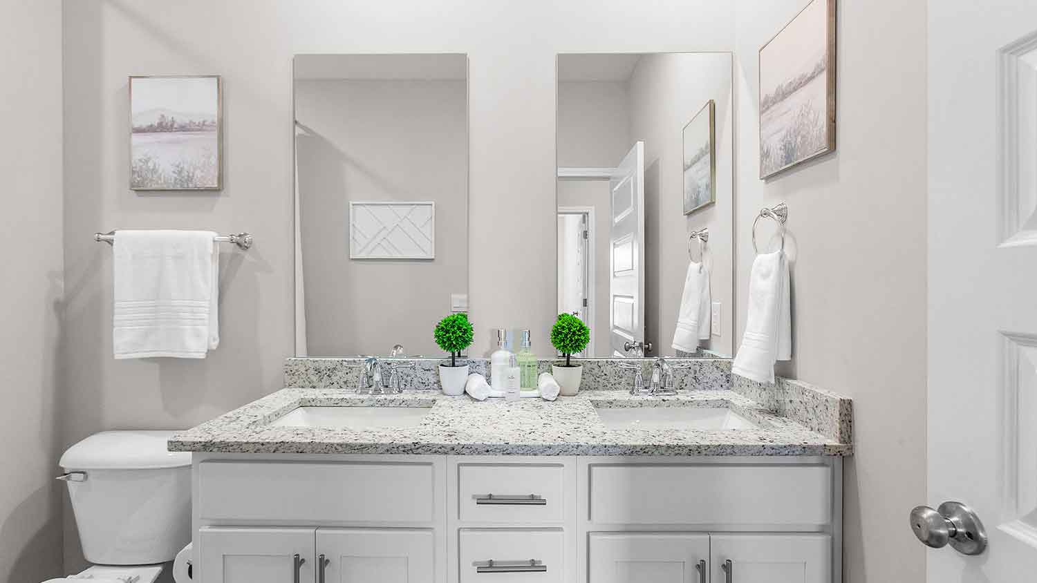 bathroom featuring dual sink vanities, a toilet and a shower