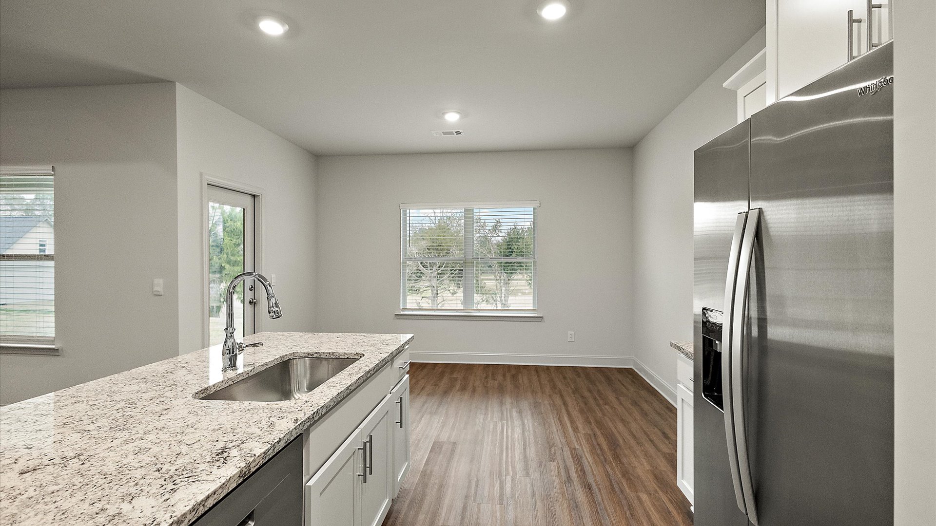 Breakfast nook area adjacent to the kitchen with hardwood flooring and windows for natural light.