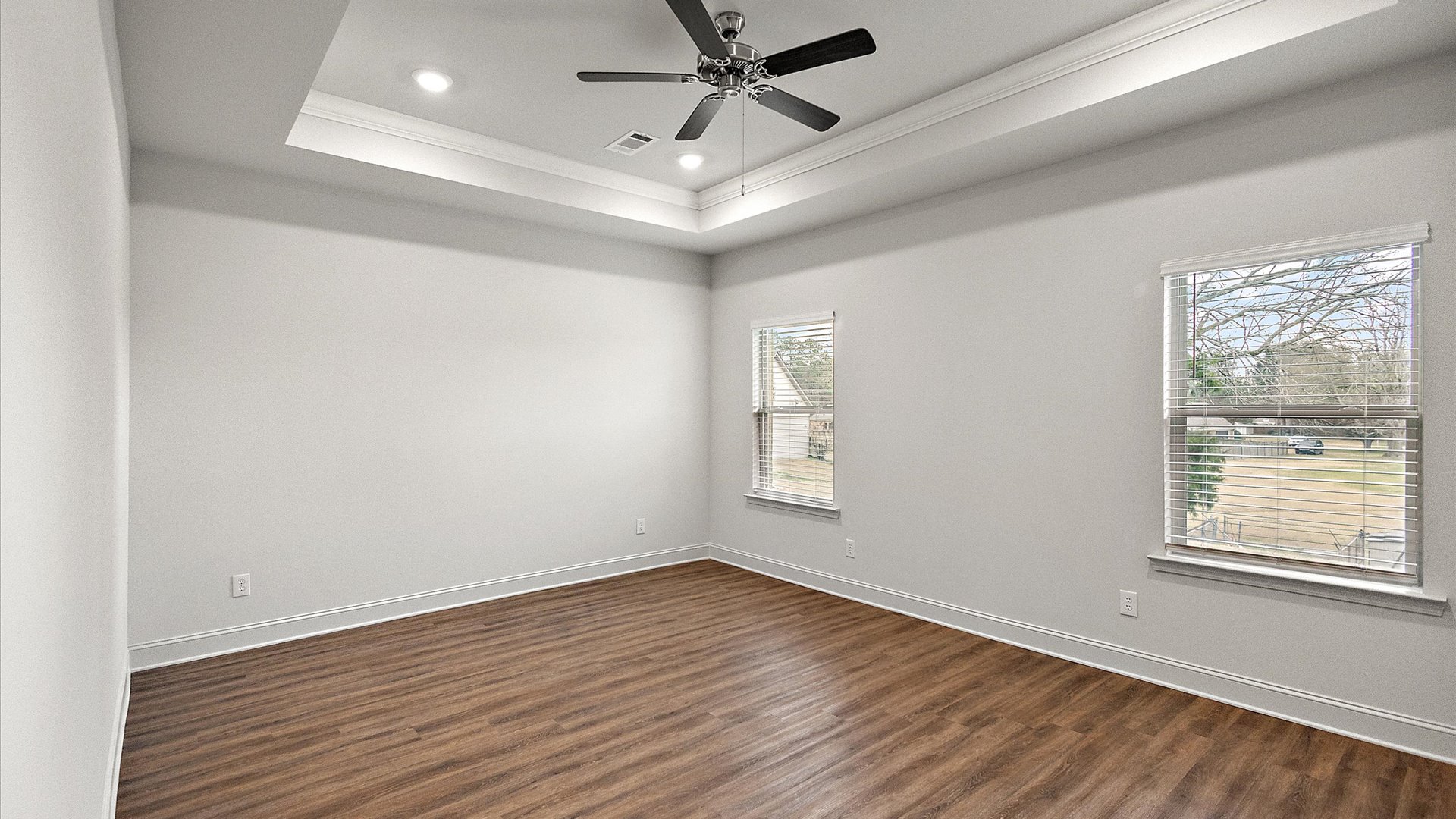The primary bedroom has recessed lighting, windows, and tray ceiling.