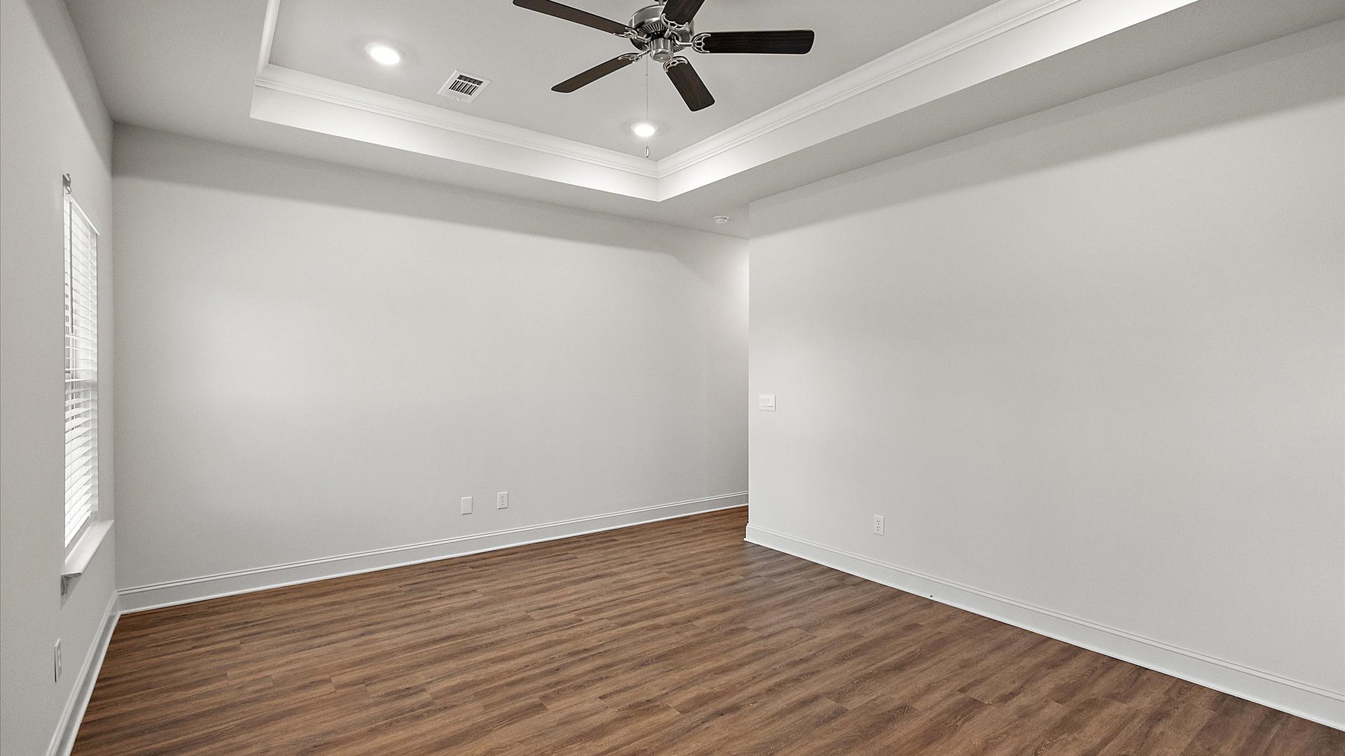 The primary bedroom has recessed lighting, windows, and tray ceiling.