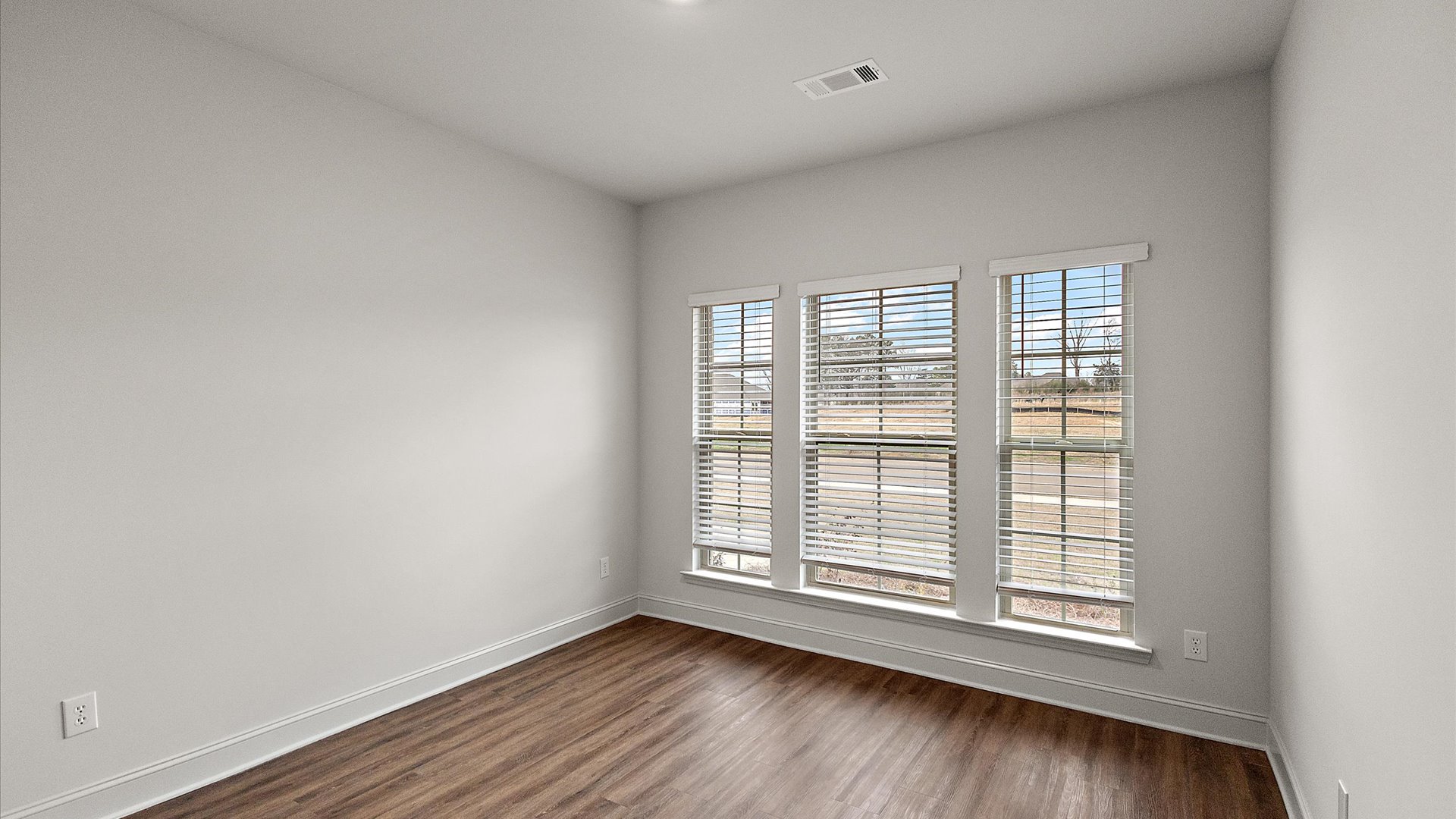 Additional room has hardwood floors, window for natural light, and recessed lighting.