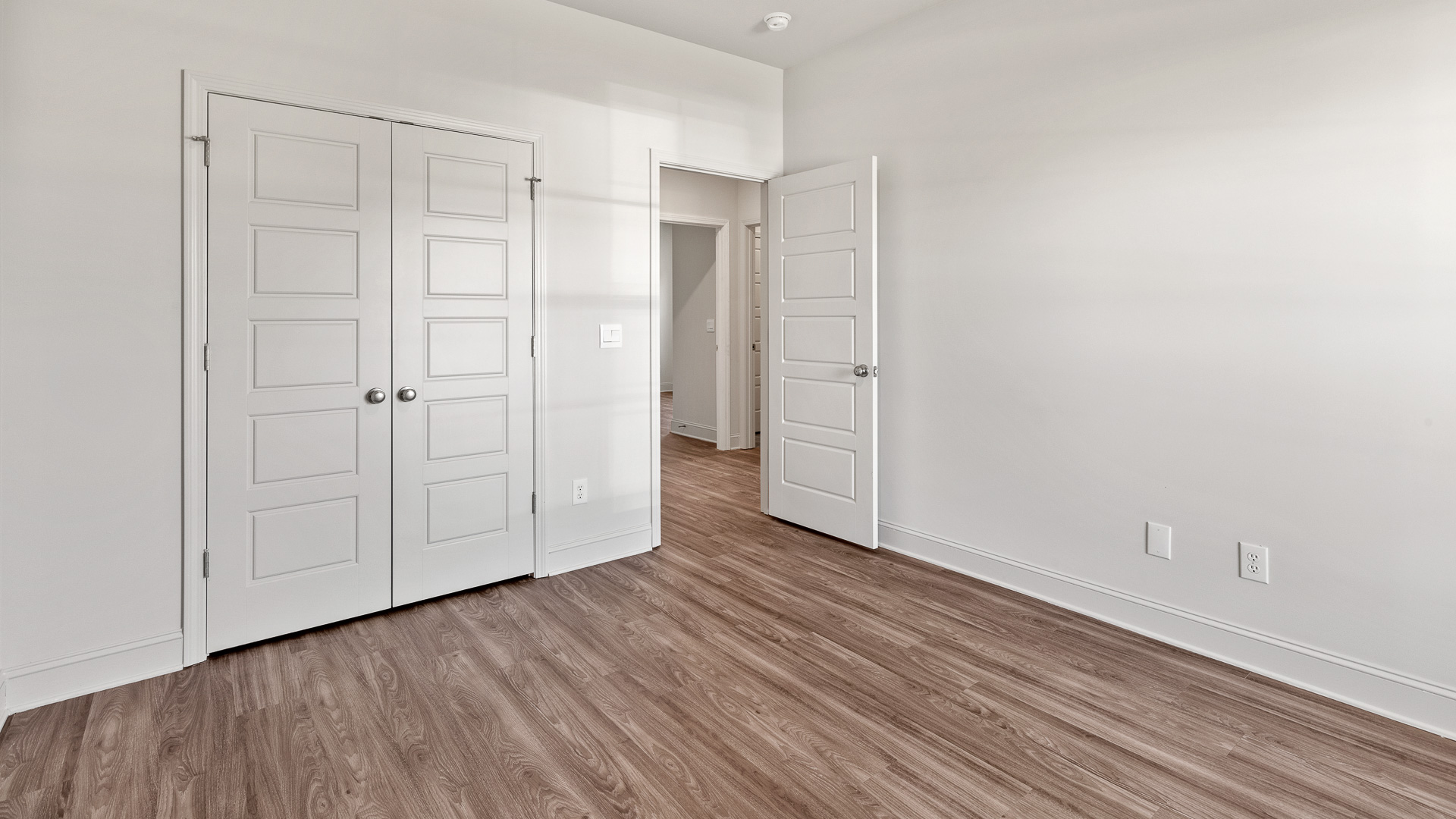 Bedroom with hardwood floors and double door closet.