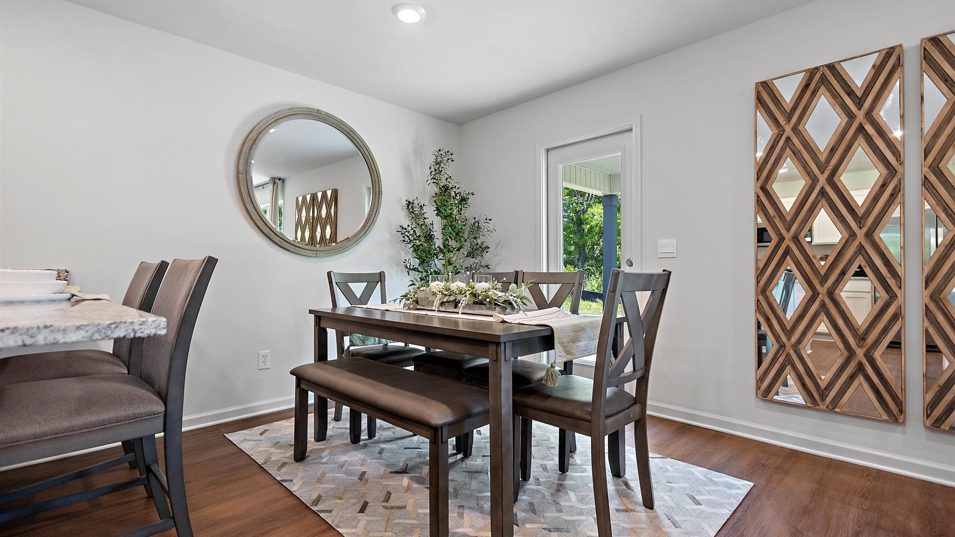 dining room with a brown rectangular table, grey rug and a faux tree in the corner