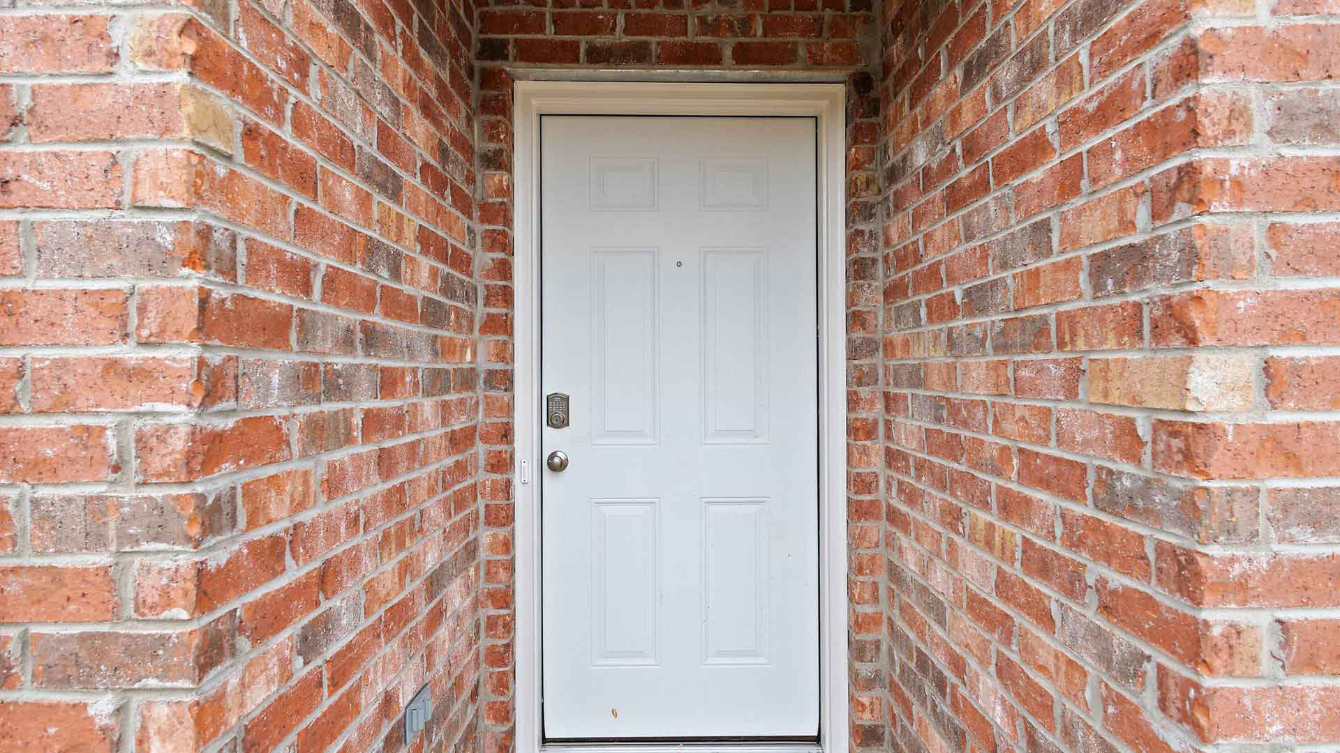 Front porch with red/brown brick and white door.