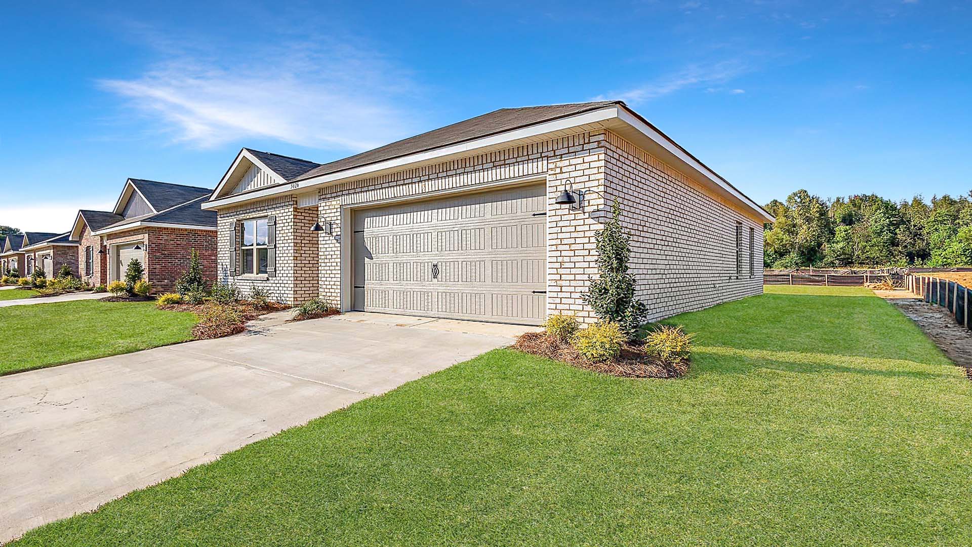 Side exterior single story home with red/brown brick and white paneling and black shutters on the windows with side walk to the front door. The two-car garage and driveway.