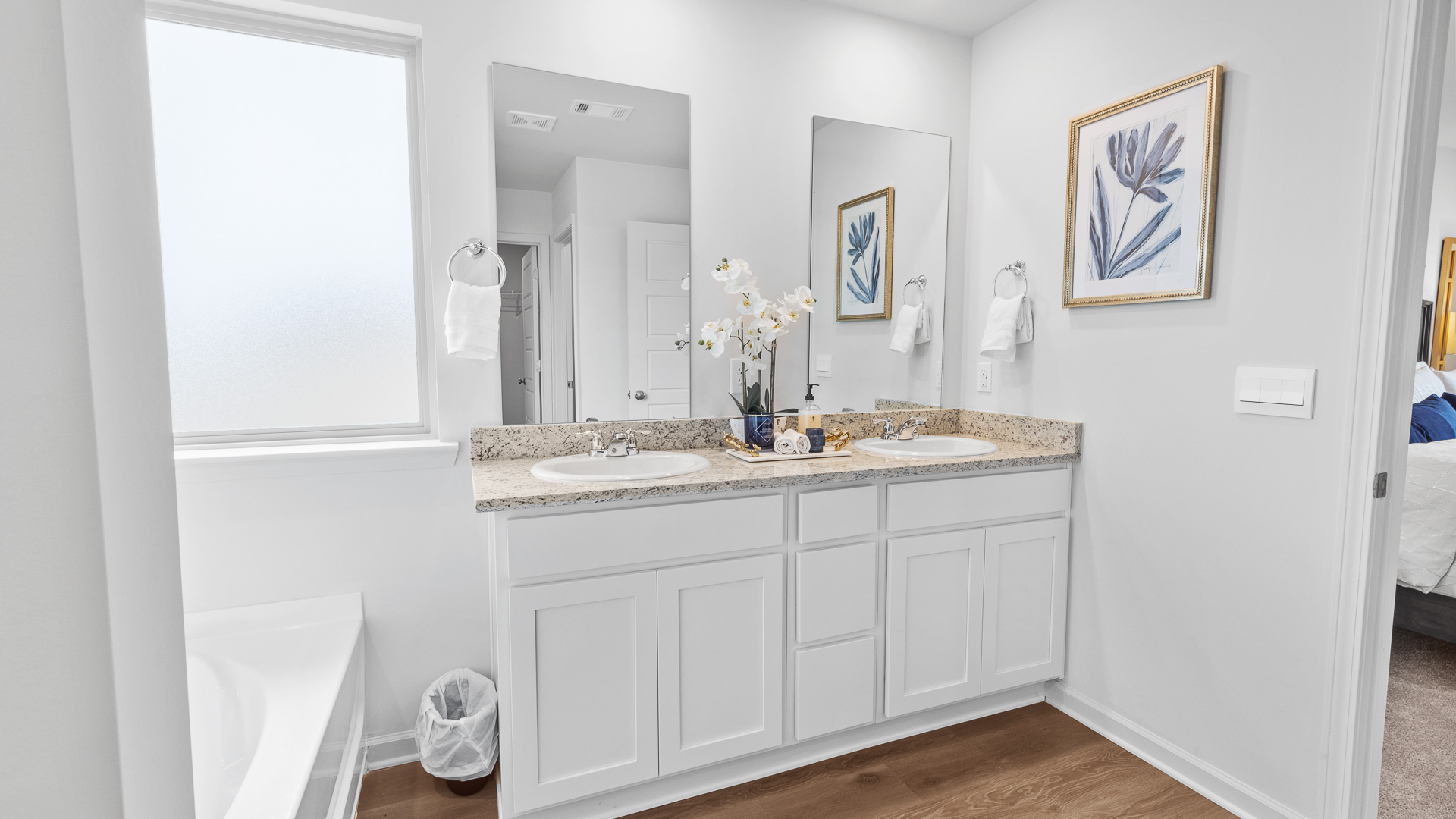 Ensuite bathroom with a double vanity sinks, granite countertops, white shaker-style cabinets and two single view mirrors over each sink.