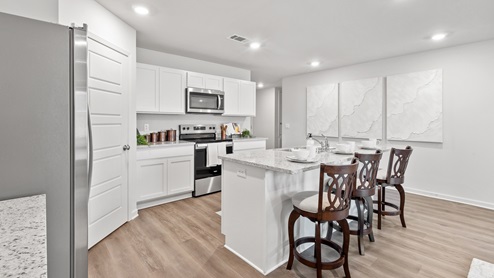 Kitchen has granite countertops, white shaker-style cabinets, an island with a sink, and stainless steel appliances.