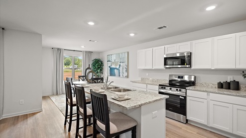 Open concept kitchen with dining area behind.