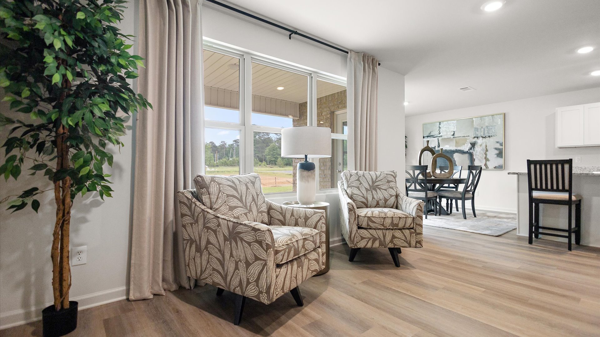 Back of the living area next to large windows with the dining area in the back next to the kitchen.