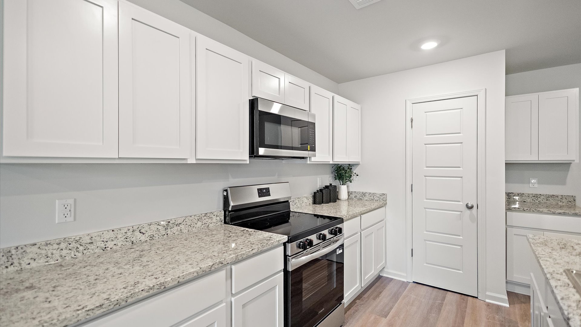 Kitchen area with white cabinets, granite countertops, and pantry in the corner.