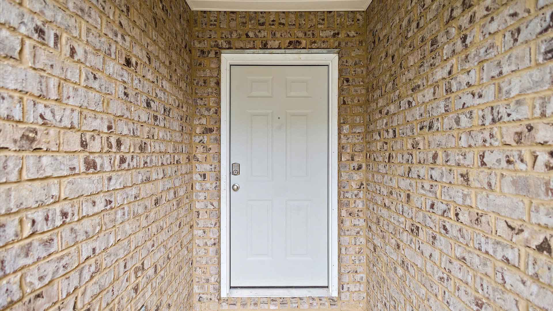 Front entrance and covered porch with tan brick on either side.