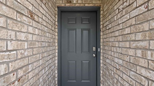 front entry way of home featuring brick exterior and a black door