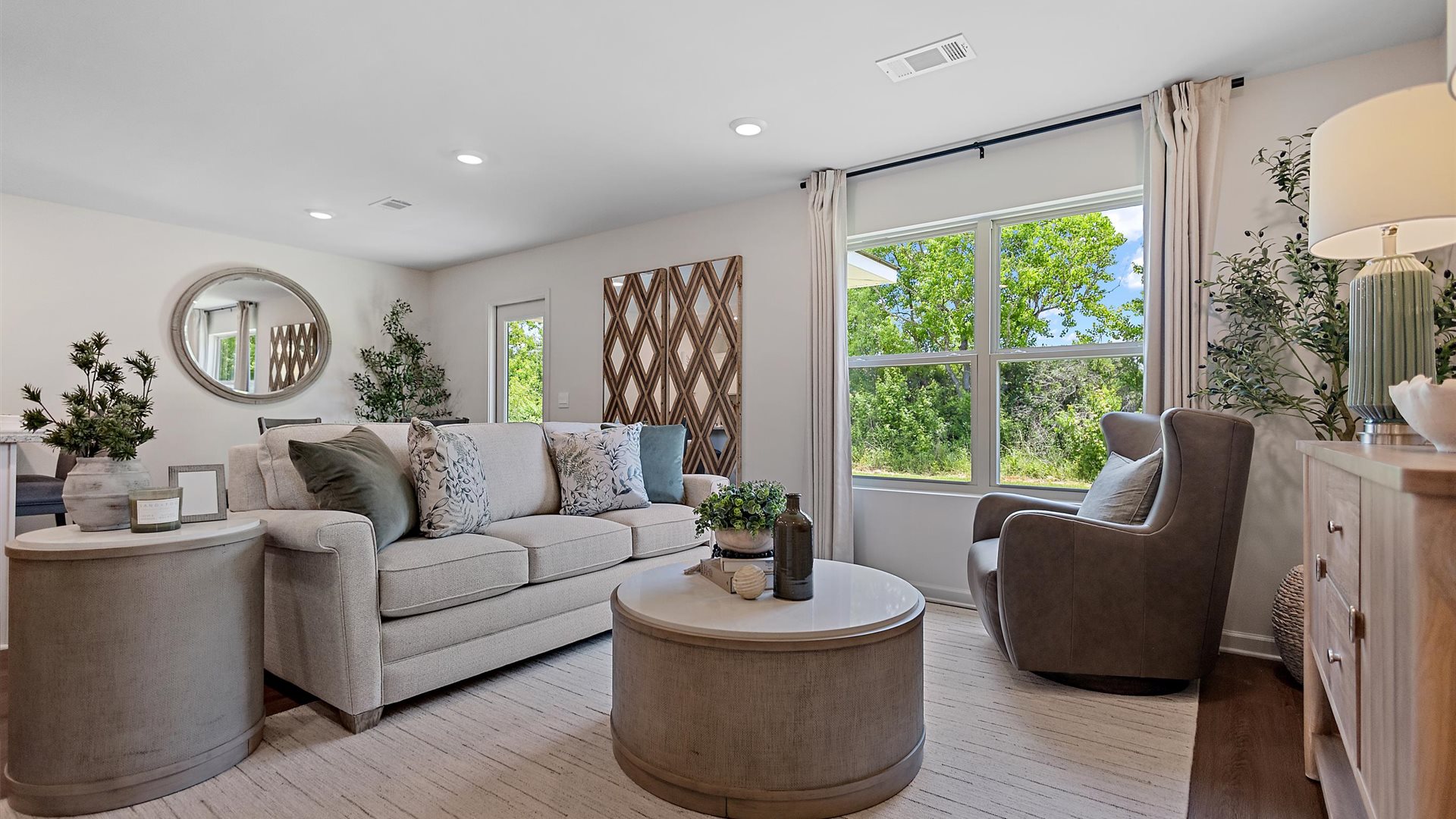 cozy living room with a beige sofa, neutral accent chairs and pops of blue decor